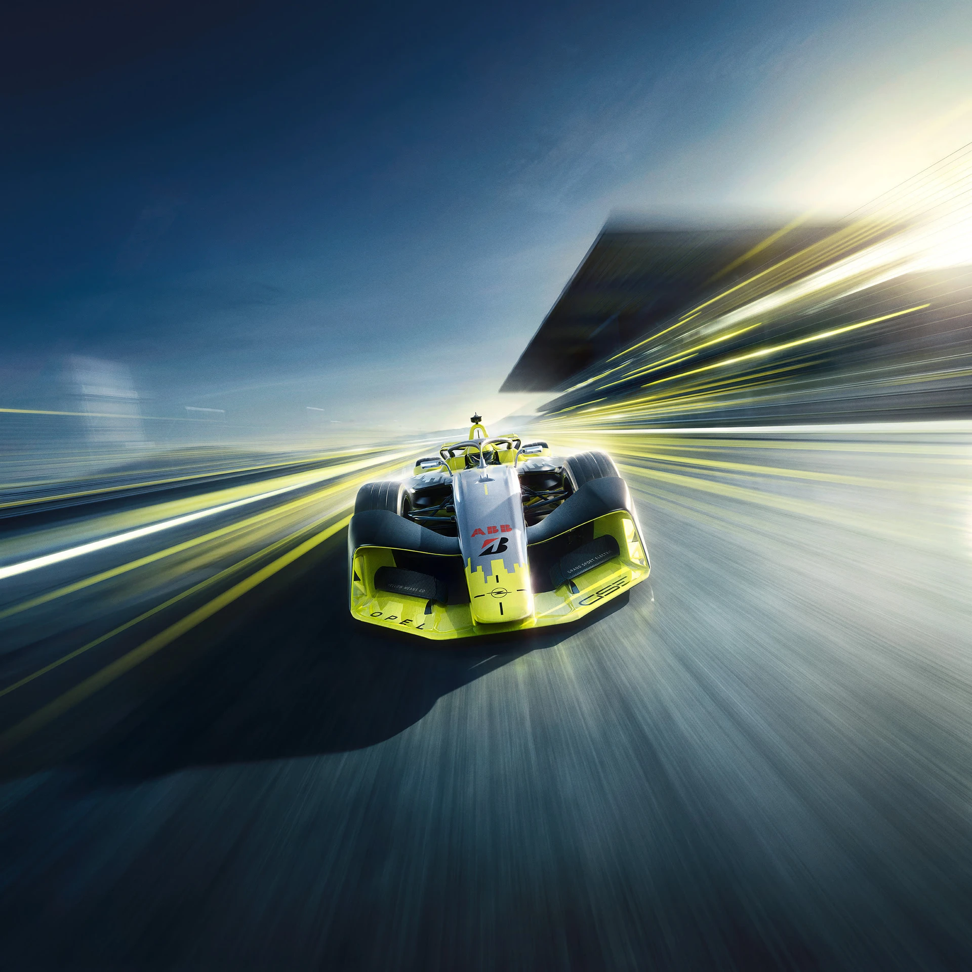 Front view of a yellow and silver Opel GSE Formula E car racing toward the viewer, surrounded by bright yellow light streaks and motion blur.