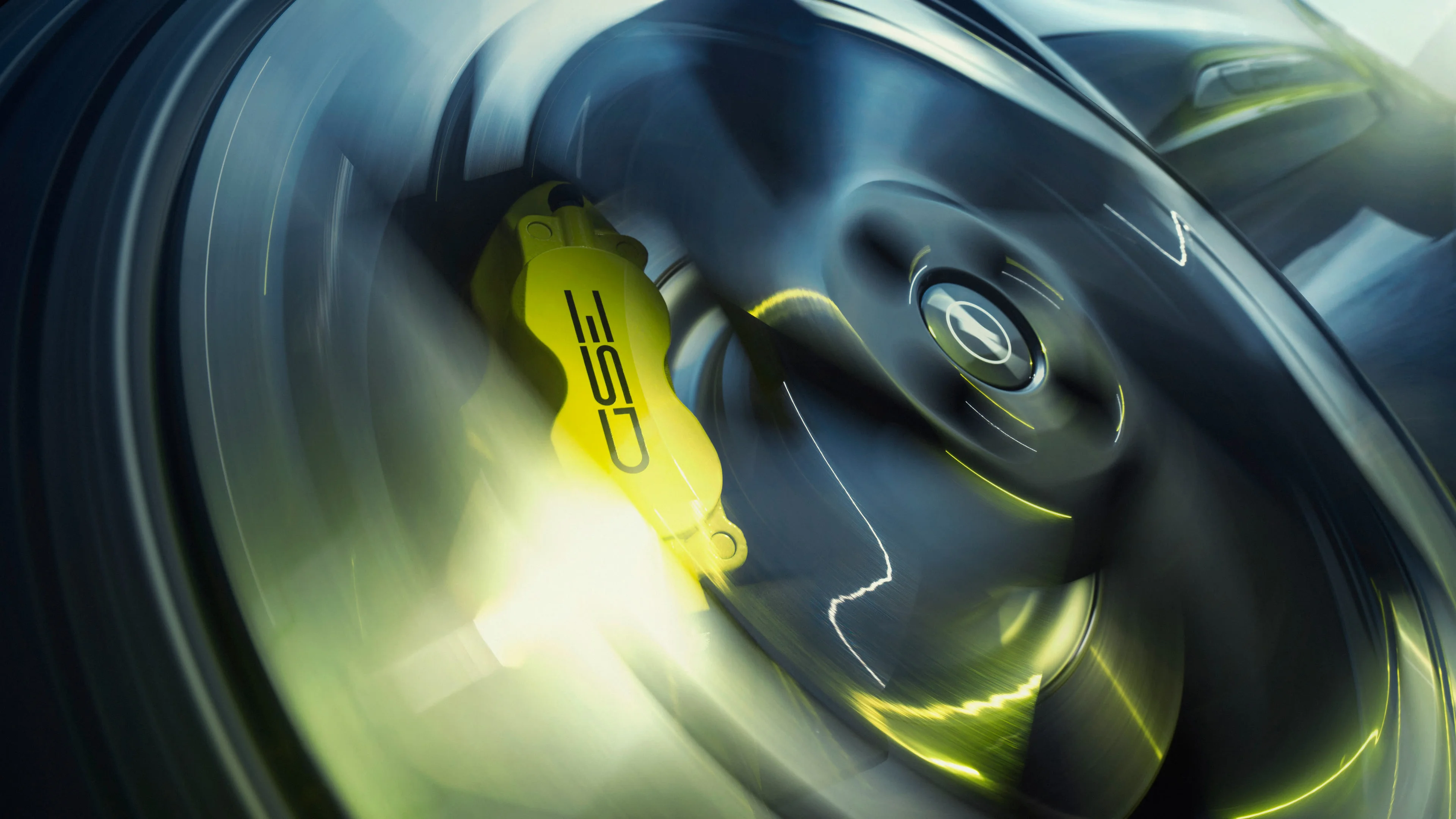 Close-up of a yellow GSE-branded brake caliper behind a dark alloy wheel with the Opel Blitz centre cap, the spokes blurred by motion.